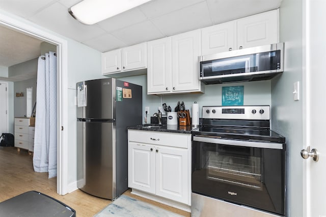 kitchen with sink, light hardwood / wood-style flooring, stainless steel appliances, white cabinets, and a drop ceiling