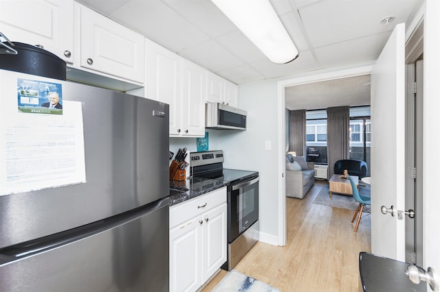 kitchen with a drop ceiling, light hardwood / wood-style flooring, stainless steel appliances, and white cabinets