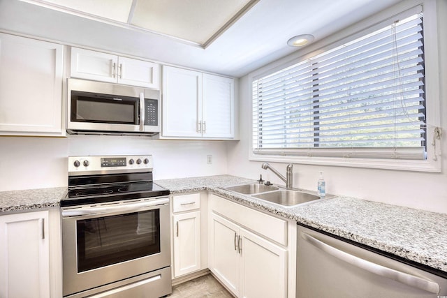 kitchen with light stone counters, sink, white cabinets, and stainless steel appliances