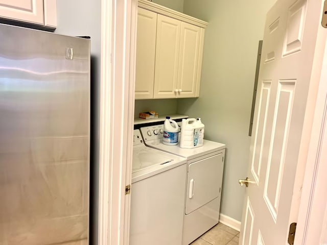 clothes washing area featuring washer and clothes dryer, light tile patterned flooring, and cabinets