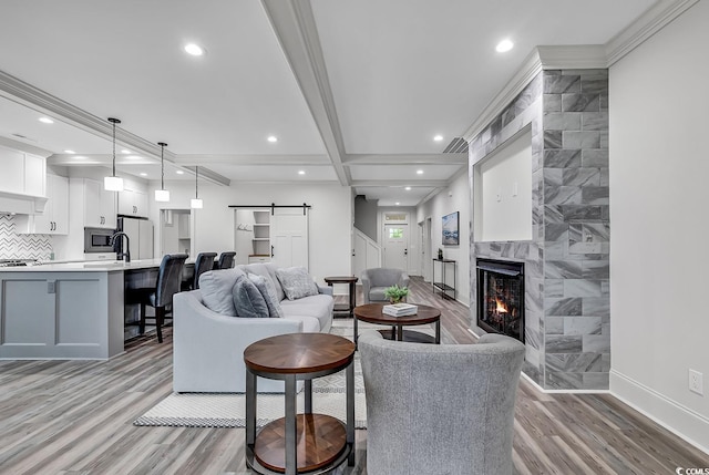 living room featuring tile walls, light wood-type flooring, a barn door, and crown molding