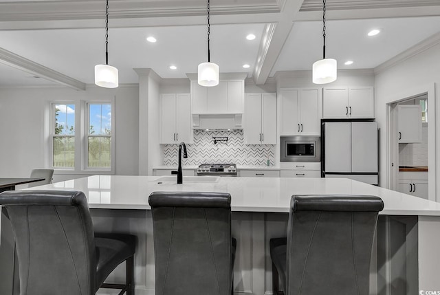 kitchen with stainless steel appliances, hanging light fixtures, white cabinets, and a large island with sink