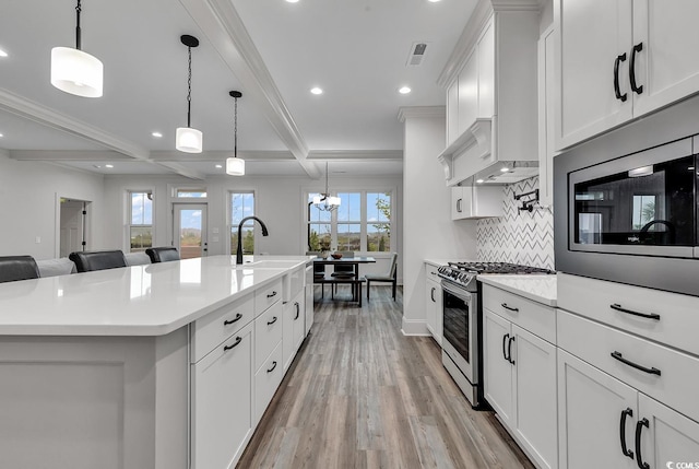 kitchen featuring plenty of natural light, decorative light fixtures, an island with sink, and stainless steel appliances