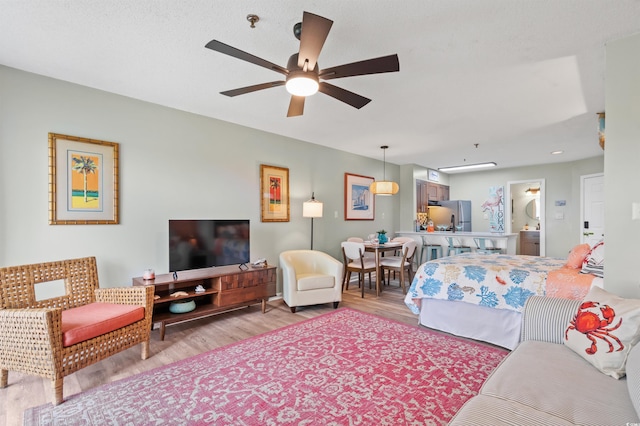 bedroom with stainless steel refrigerator, ceiling fan, ensuite bathroom, and light hardwood / wood-style floors