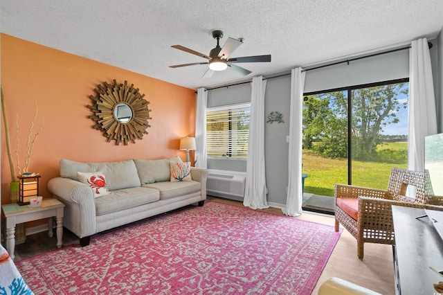 living room featuring ceiling fan and a textured ceiling