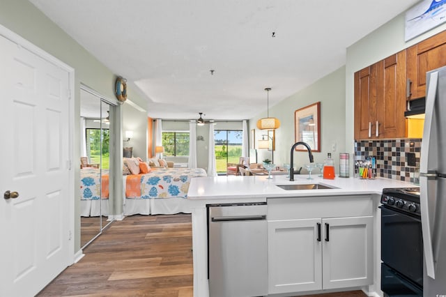 kitchen with hardwood / wood-style floors, black stove, kitchen peninsula, sink, and white cabinetry