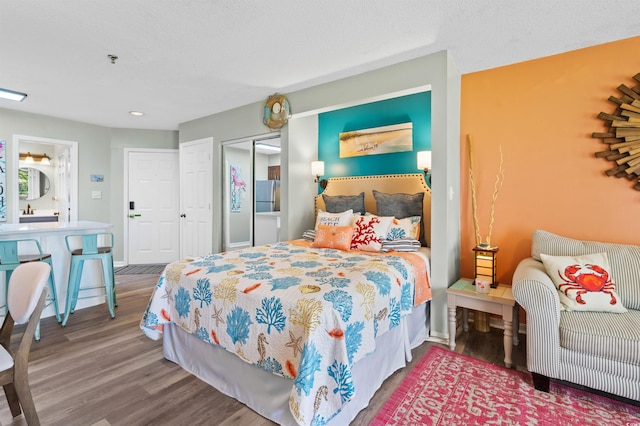 bedroom with hardwood / wood-style flooring and stainless steel fridge