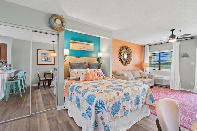 bedroom with ceiling fan, a closet, wood-type flooring, and a textured ceiling