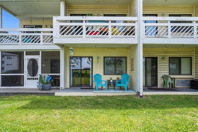 rear view of property with a patio, a balcony, and a lawn