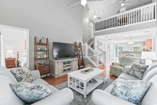 living room with hardwood / wood-style flooring, ceiling fan, and a towering ceiling