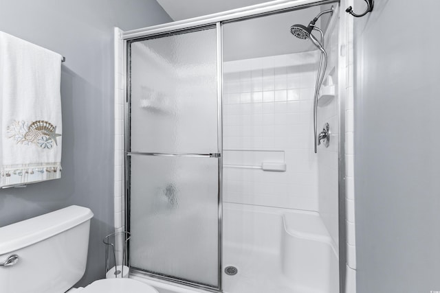 bathroom with a shower with shower door and toilet