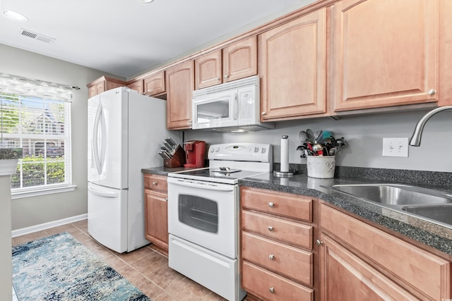 kitchen with sink, light tile patterned floors, light brown cabinetry, and white appliances