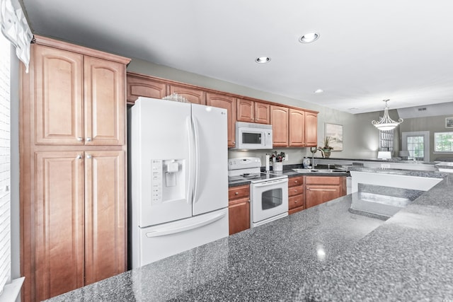 kitchen with hanging light fixtures, white appliances, and sink