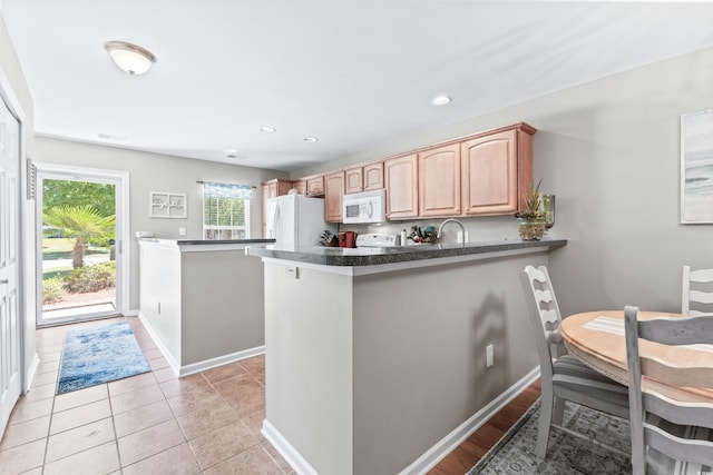 kitchen featuring white appliances, kitchen peninsula, and light tile patterned floors