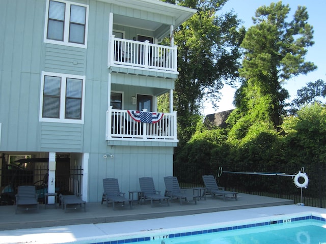 back of house featuring a balcony and a fenced in pool