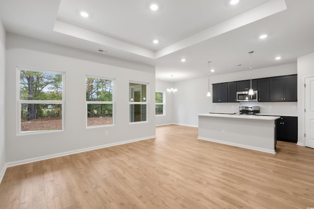 kitchen with plenty of natural light, an island with sink, appliances with stainless steel finishes, and light hardwood / wood-style flooring