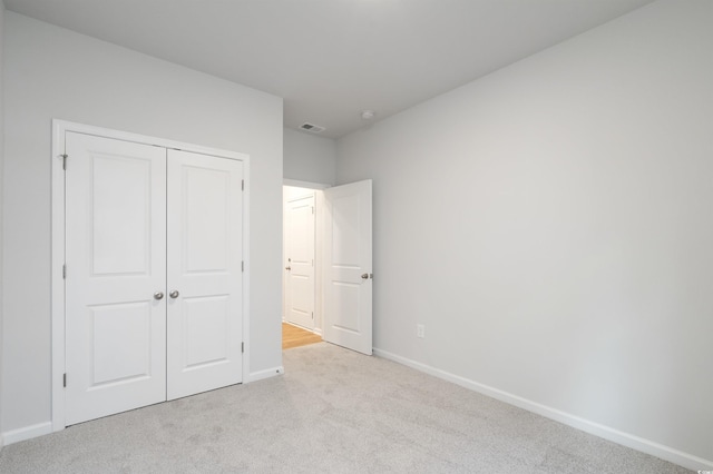 unfurnished bedroom featuring light colored carpet and a closet