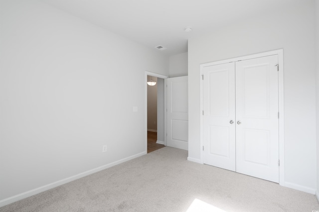 unfurnished bedroom with light colored carpet and a closet