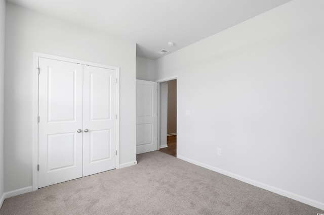 unfurnished bedroom with light colored carpet and a closet