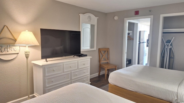 bedroom with stainless steel fridge and dark hardwood / wood-style flooring