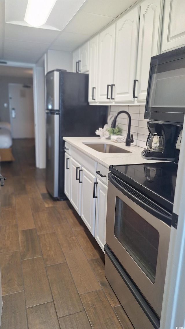 kitchen with white cabinetry, sink, dark hardwood / wood-style floors, backsplash, and stainless steel electric range