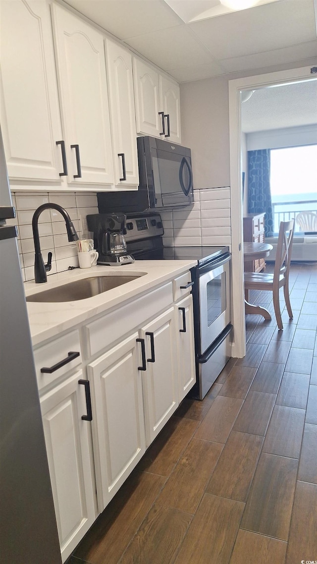 kitchen with backsplash, dark wood-type flooring, sink, electric range, and white cabinetry