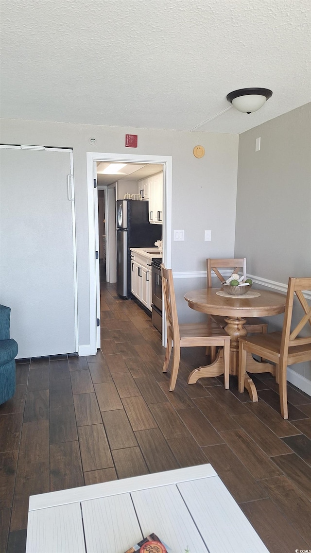 dining room with a textured ceiling and dark wood-type flooring