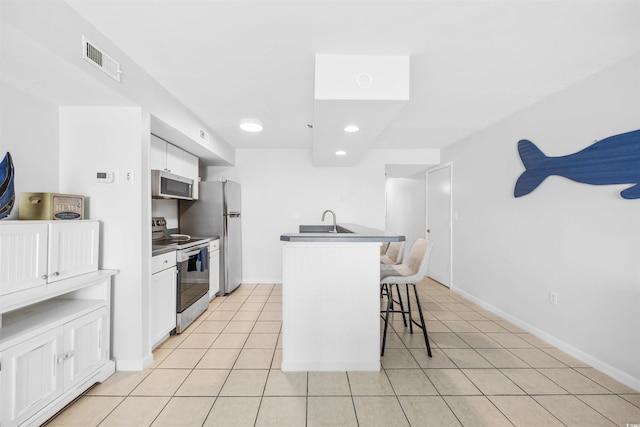 kitchen with a kitchen breakfast bar, white cabinetry, an island with sink, and appliances with stainless steel finishes