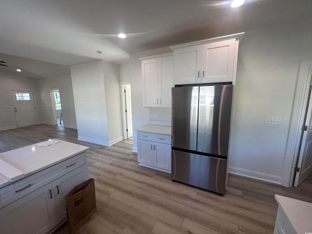 kitchen featuring white cabinets, light wood-type flooring, lofted ceiling, and stainless steel fridge