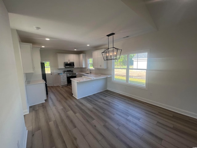 kitchen featuring white cabinetry, appliances with stainless steel finishes, decorative light fixtures, and light hardwood / wood-style floors