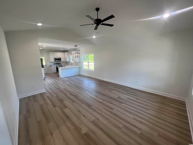 unfurnished living room featuring light hardwood / wood-style floors, ceiling fan, sink, and lofted ceiling