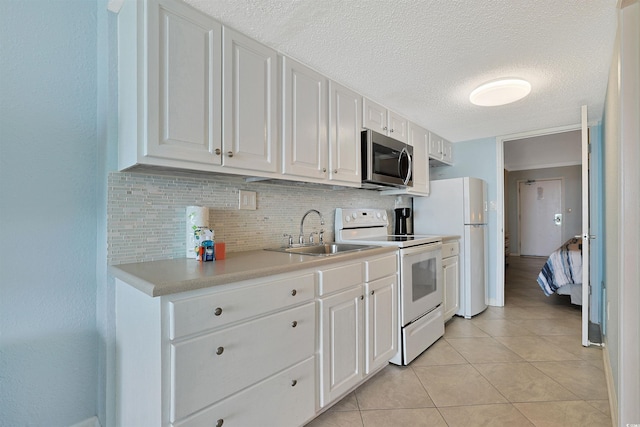 kitchen featuring light countertops, white appliances, a sink, and white cabinetry