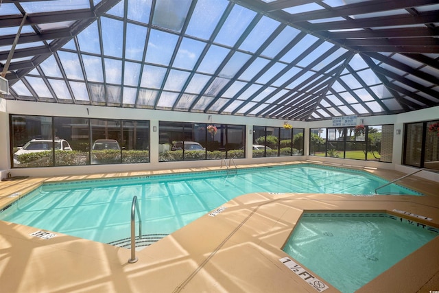 view of swimming pool featuring glass enclosure and a community hot tub