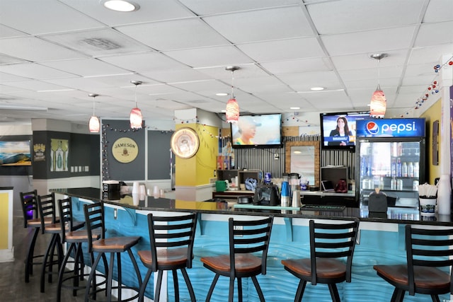 bar with hanging light fixtures, a dry bar, and a drop ceiling