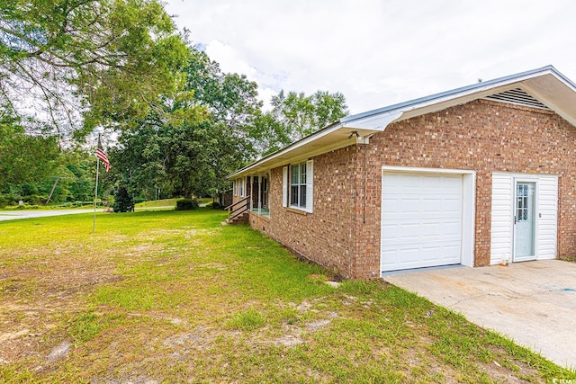 view of side of property featuring an attached garage, a yard, brick siding, and driveway