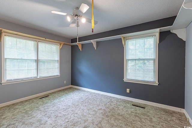 empty room with visible vents, carpet, ceiling fan, and a textured ceiling