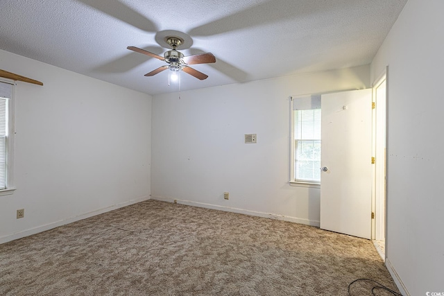 empty room with a textured ceiling, carpet, baseboards, and ceiling fan