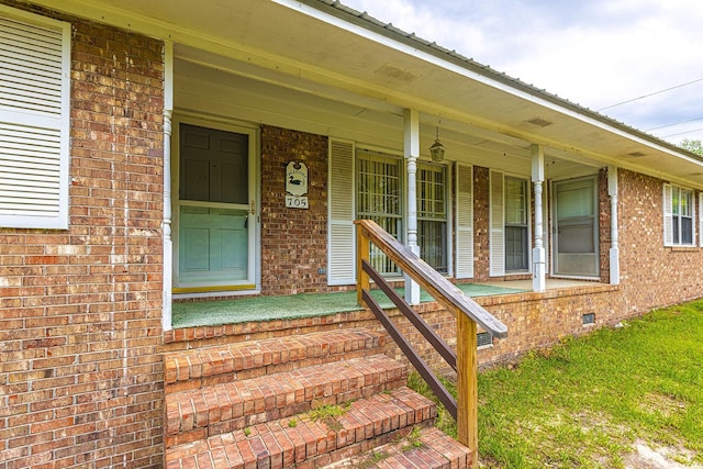 property entrance with covered porch, brick siding, and crawl space