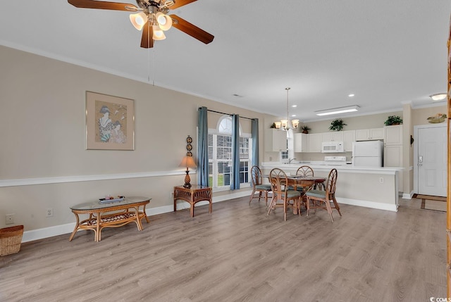 dining area featuring baseboards, crown molding, light wood finished floors, and ceiling fan with notable chandelier