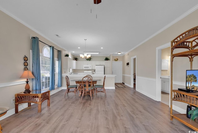 dining space featuring ornamental molding, a chandelier, and light wood-style flooring