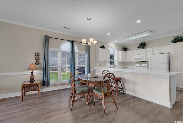 dining area with light wood-type flooring, baseboards, and ornamental molding