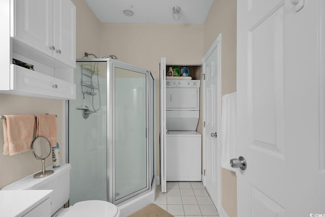 full bathroom featuring stacked washer / dryer, a shower stall, toilet, and tile patterned floors