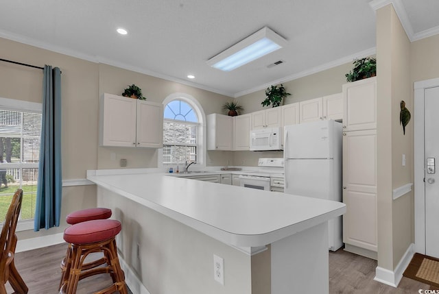 kitchen featuring light countertops, white appliances, a breakfast bar area, and white cabinets