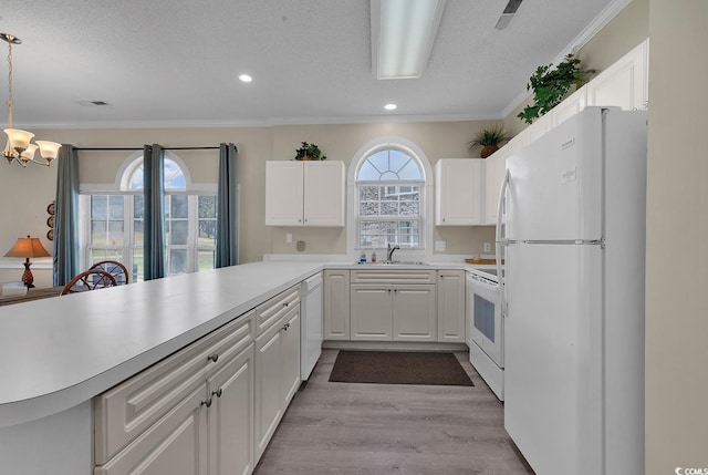 kitchen featuring hanging light fixtures, white appliances, white cabinets, and light countertops