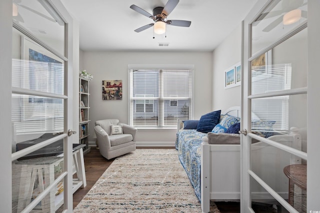 living area featuring french doors, ceiling fan, a healthy amount of sunlight, and dark hardwood / wood-style floors