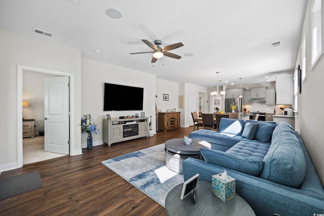 living room featuring dark wood-type flooring and ceiling fan with notable chandelier