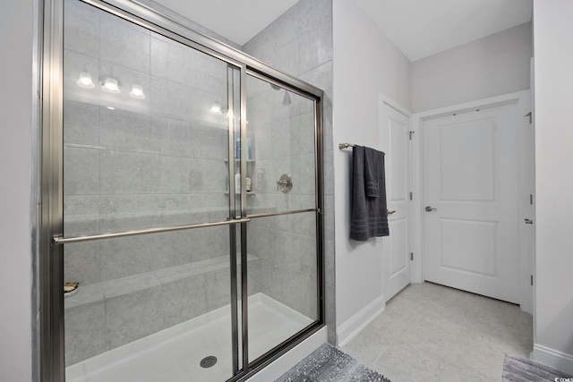 bathroom with a shower with door and tile patterned floors