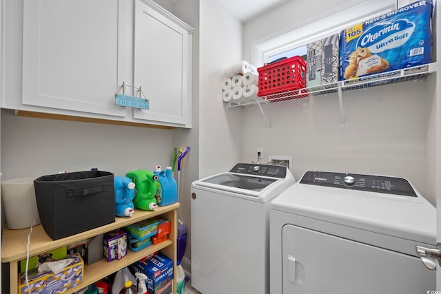 clothes washing area with washer and clothes dryer and cabinets