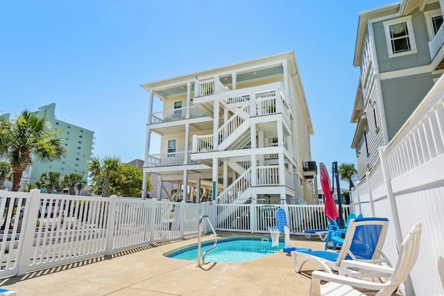 rear view of house featuring a fenced in pool and a patio