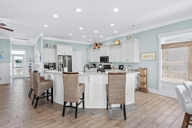 kitchen featuring a breakfast bar, white cabinetry, stainless steel fridge, a large island, and black range